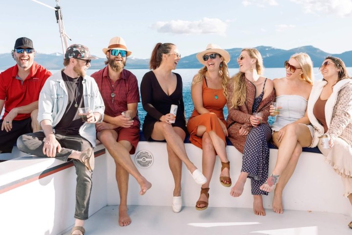 Group of people sitting on a boat with a scenic mountain and water view.