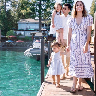 Family walking on a dock near boats and clear water.