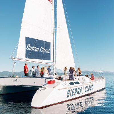 Group sailing on a white catamaran boat named Sierra Cloud under clear skies.
