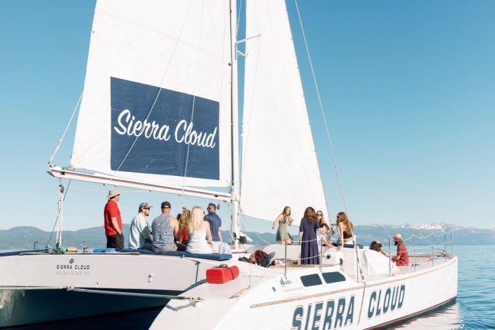 Group sailing on a white catamaran boat named Sierra Cloud under clear skies.