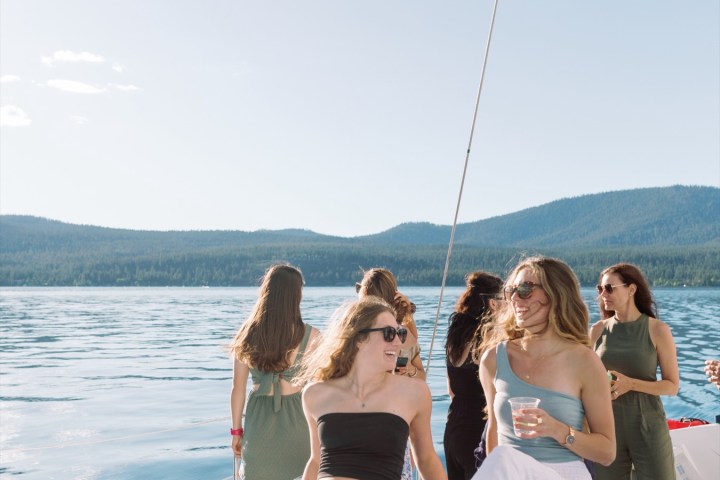 Group of women relaxing on a boat with a mountain and lake view.
