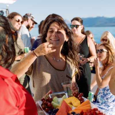 People enjoy a sunny outdoor gathering with fruit platter and drinks.
