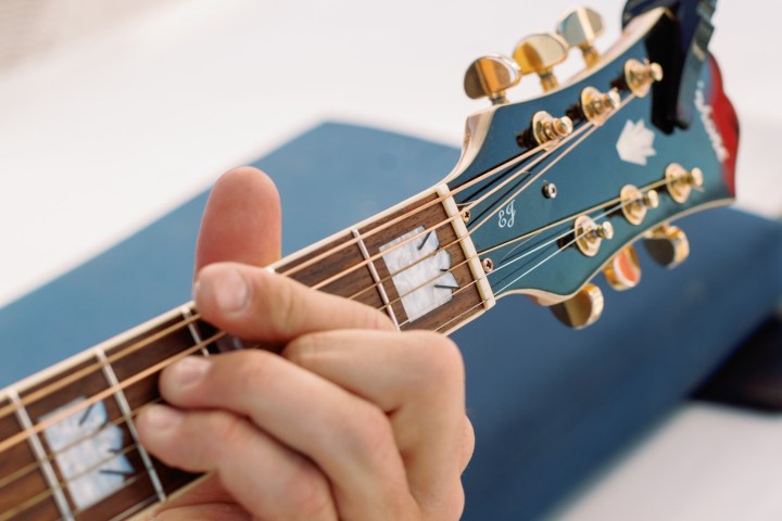 Close-up of a hand playing a guitar on a sunny day.